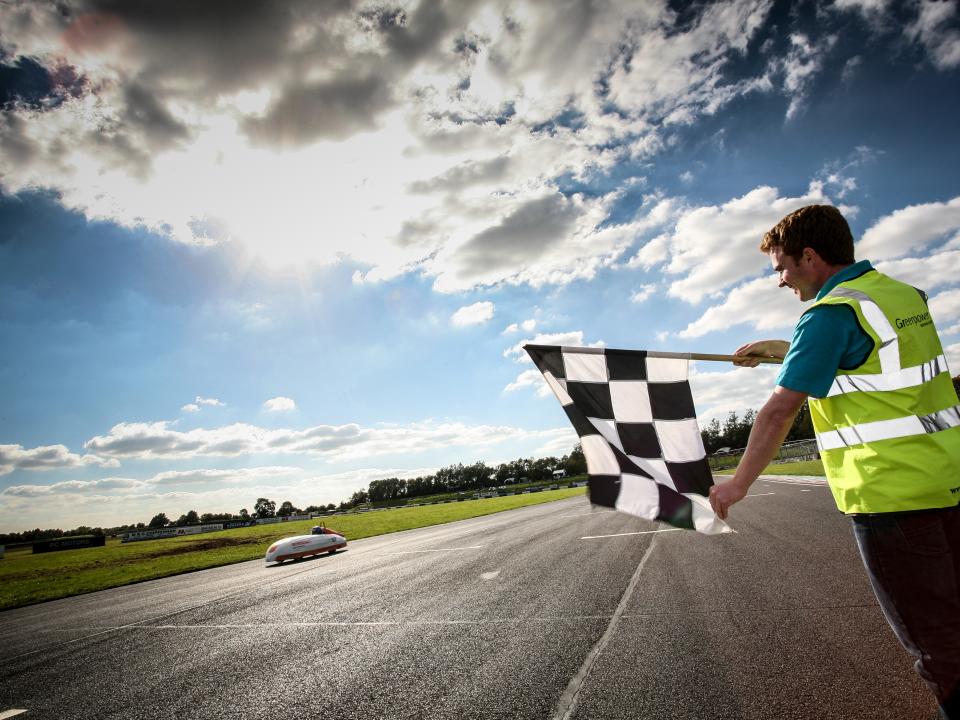man in yellow jacket waving flag